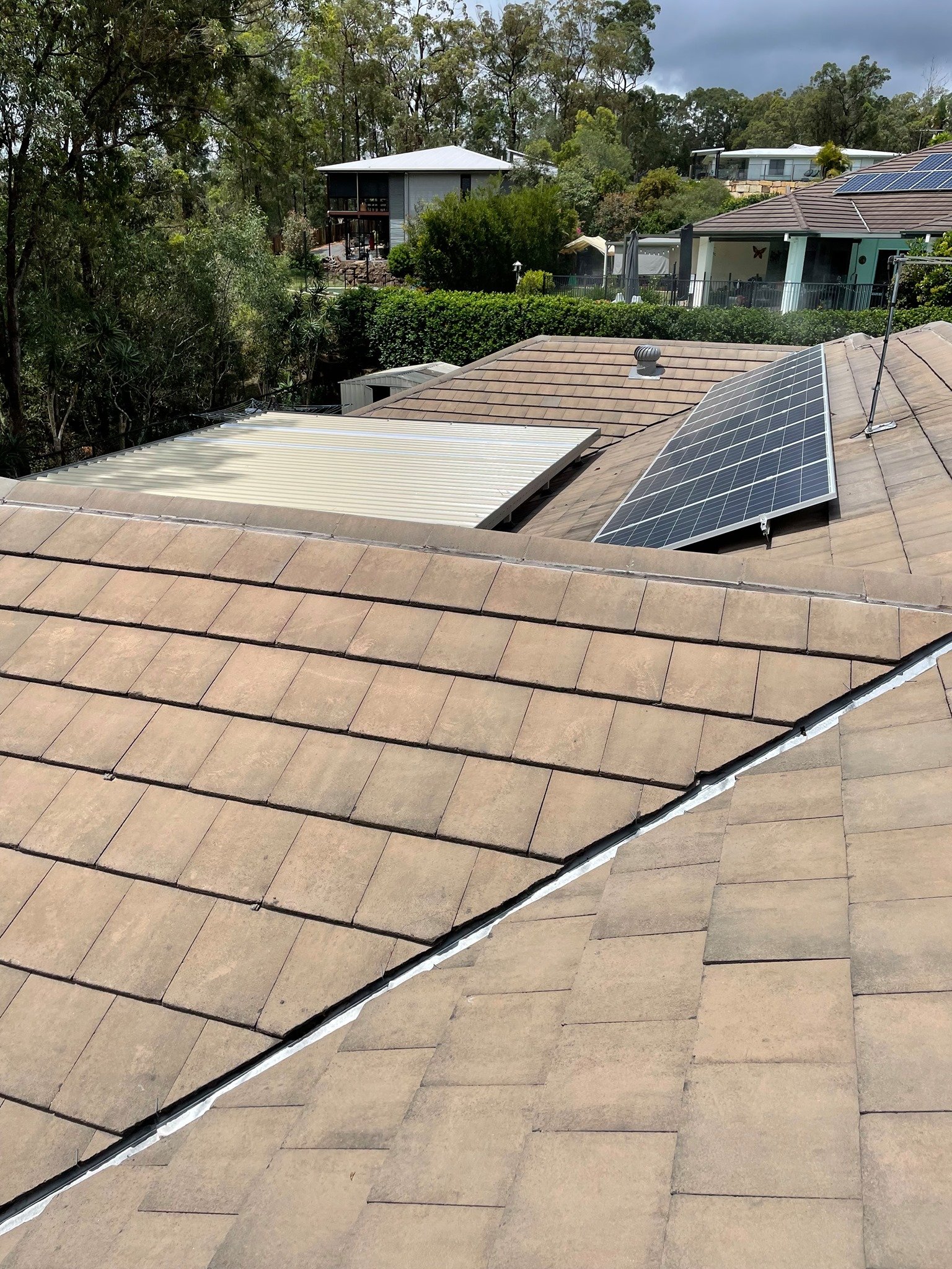 Roofer inspecting tiled roof for cracks and damage in Brisbane property